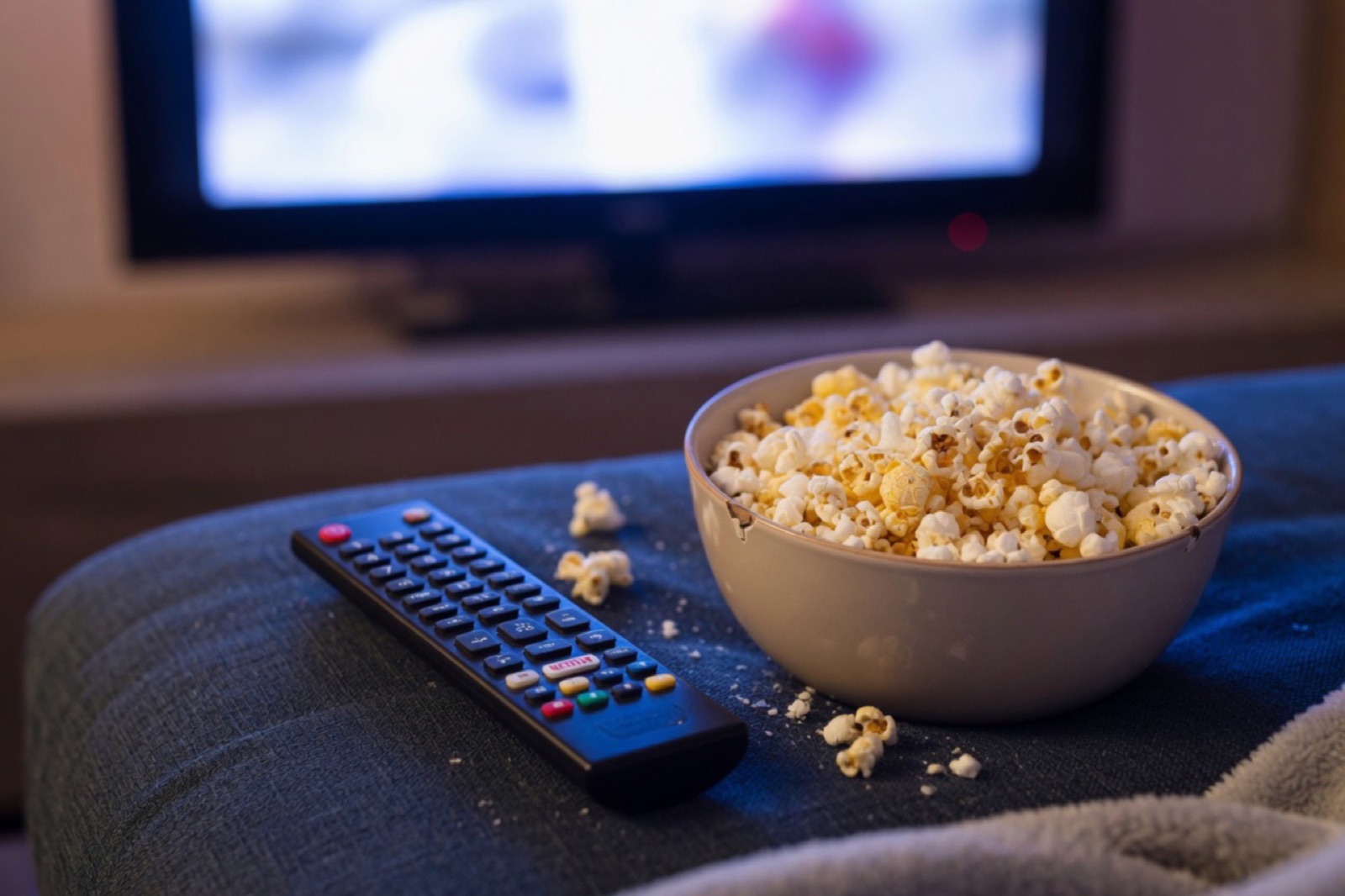 A remote and popcorn on the couch during movie night